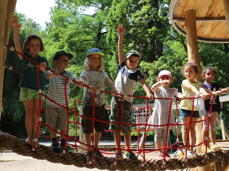 Kinder winken von einem Klettergerüst
