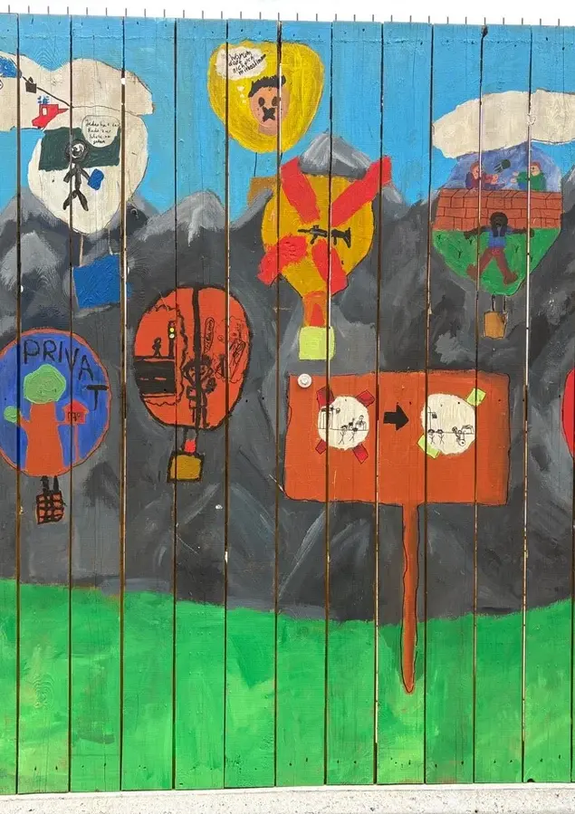 Nahaufnahme bunter Bilder, die am Bauzaun von Kindern erstellt wurden.