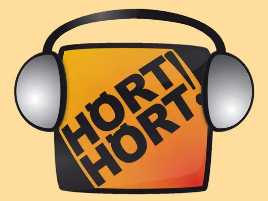 Kasten, in dem Hört Hört! steht mit Kopfhörern. Klick öffnet Bild in größerer Ansicht.