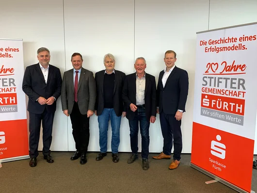 Genannte Personen, an der Seite Plakat mit Sparkassen-Logo und Text: Die Geschichte eines Erfolgsmodelles. 20 Jahre Stiftergemeinschaft Sparkasse Fürth. Wir stiften Werte. Klick öffnet die Meldung.