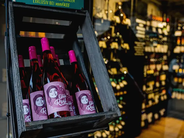 In der Auslage eines Feinkostgeschäfts eine Kiste mit Rose-Glühwein mit dem Namen "Glüh-Rosl"