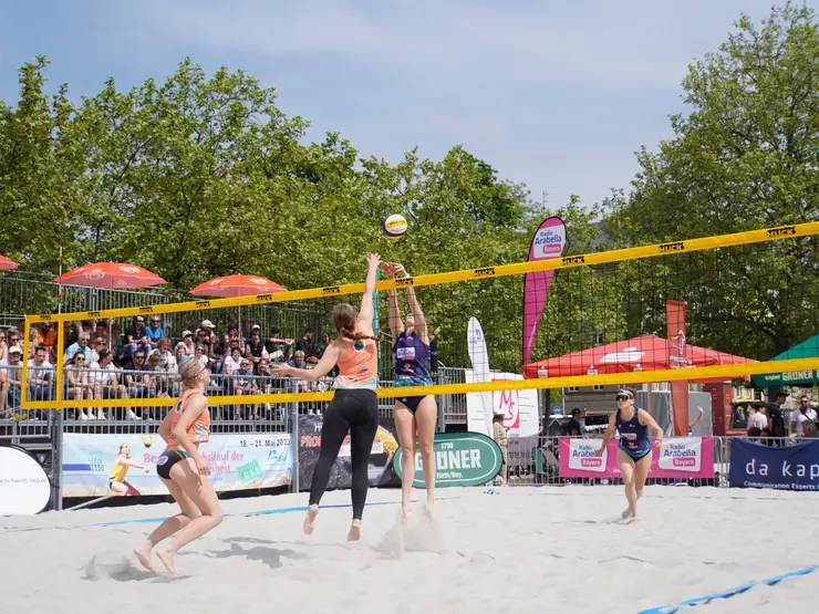 Vier Beachvolleyballerinnen und Publikum beim Cup auf der Freiheit; Klick auf Bild öffnet Veranstaltungshinweis.