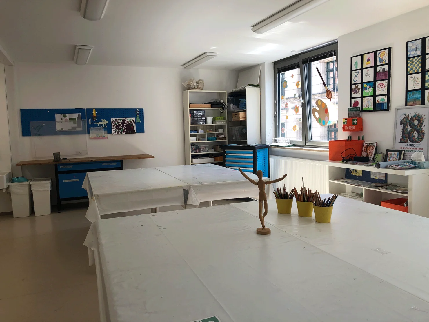 Große Tische im Werkraum bieten viel Platz. In den Regalen verschiedene Materialien.