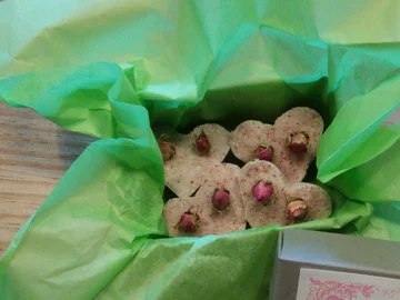 Herzförmige Seifen mit getrockneten Rosenknospen auf grünem Seidenpapier in einer Schachtel