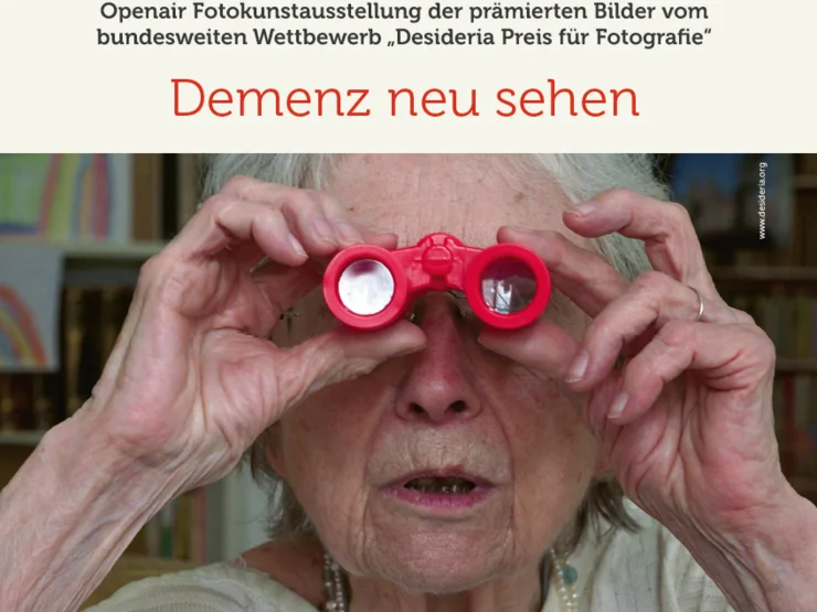 Ältere Person hält rote Spielzeugferngläser vor die Augen