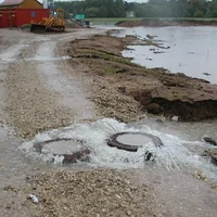  Rückstau in der Kanalisation, bei dem Wasser aus den Kanaldeckeln auf der Straße austritt.