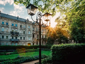 Historische Straßenlaterne mit Kleeblattsymbol, im Hintergrund die Luisenanlage und eine Häuserzeile der Hornschuchpromenade
