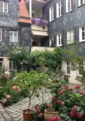 Blick in einen aufwändig begrünten Innenhof, umrahmt von schwarzen Schieferfassaden.