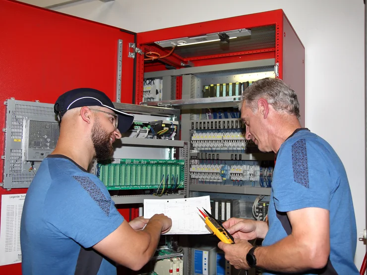 Zwei Mitarbeiter, die Arbeiten an einem Gerät durchführen. 