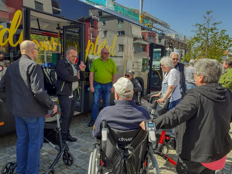 Seniorinnen und Senioren, teils im Rollstuhl, teils mit Rollator nehmen an einem Sicherheitstraining für öffentliche Verkehrsmittel teil.