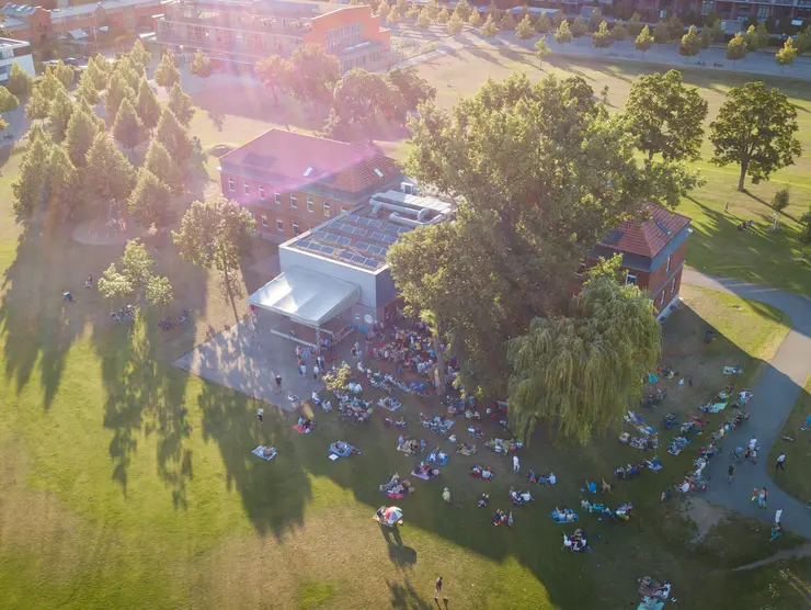 Luftaufnahme des Gebäudes der Musikschule im Südstadtpark. Vor dem Haus findet ein Open-Air-Konzert mit Publikum statt. Klick auf Bild öffnet Veranstaltungshinweis.