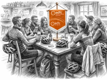 Bleistiftzeichnung einer Gruppe von Menschen an einem Holztisch in einer Bar mit Fahrradhelmen und einem Banner des Allgemeinen Deutschen Fahrrad-Clubs (ADFC) in der Mitte