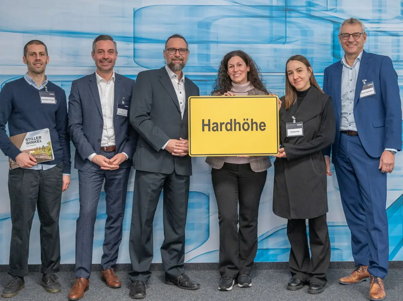 Menschen halten das Ortsschild "Hardhöhe" in den Händen.