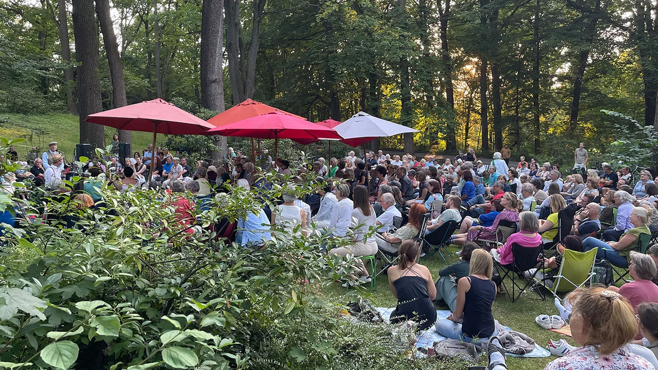 Publikum bei einer Lesung auf Decken und Klappstühlen im Stadtpark Fürth