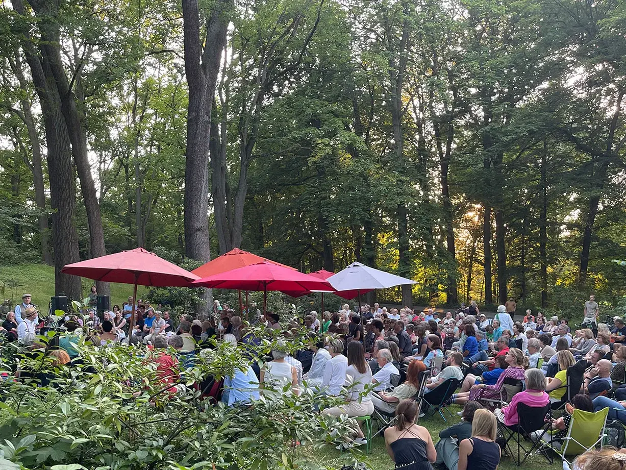 Publikum bei einer Lesung auf Decken und Klappstühlen im Stadtpark Fürth