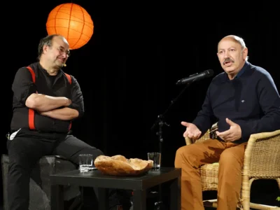 Moderator und Geschichtenerzähler Martin Ellrodt unterhält sich mit einer Teilnehmerin auf der Bühne des Kulturforums.