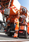 Zwei Mitarbeiter, die an einem Hochdruckspülfahrzeug stehen. 