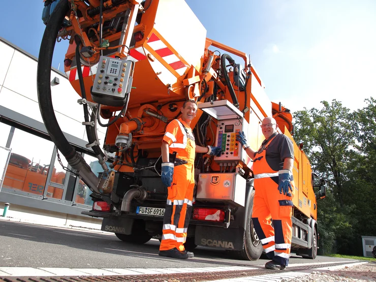 Zwei Mitarbeiter, die an einem Hochdruckspülfahrzeug stehen. 