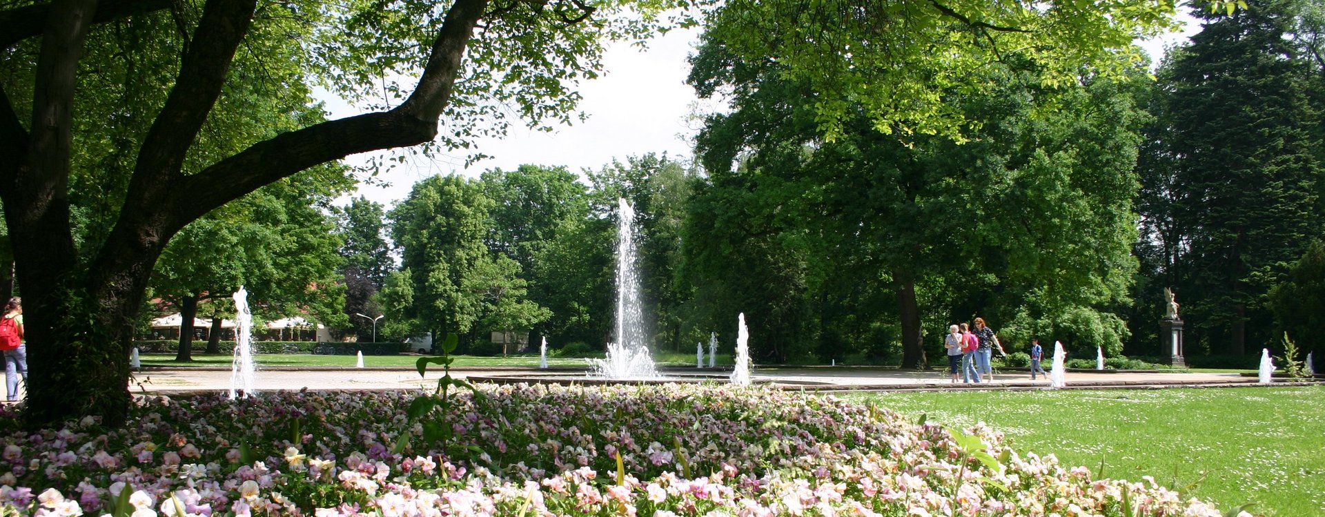 Springbrunnen im Stadtpark Fürth, im Vordergrund blühende Rabatten