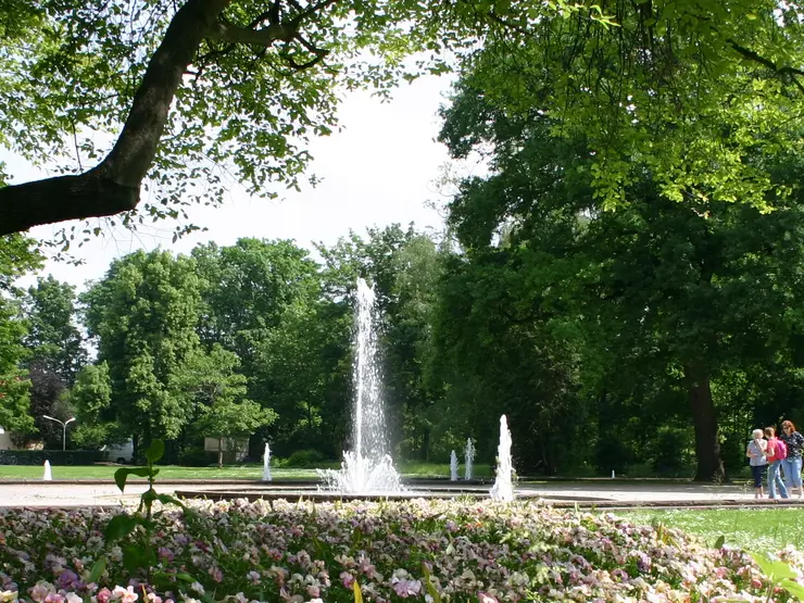 Springbrunnen im Stadtpark Fürth, im Vordergrund blühende Rabatten
